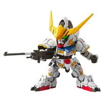 Front view of Bandai SD Gundam Ex-Standard Barbatos model kit in white, yellow, and red, holding a black rifle.