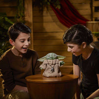 Two children smiling at a Hasbro Star Wars The Mandalorian Animatronic Edition figure wearing a silver pendant.