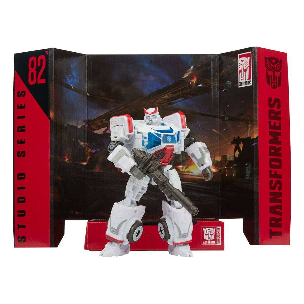 Hasbro Transformers Studio Series Autobot Ratchet action figure in white and red armor, posed with a blaster in packaging.
