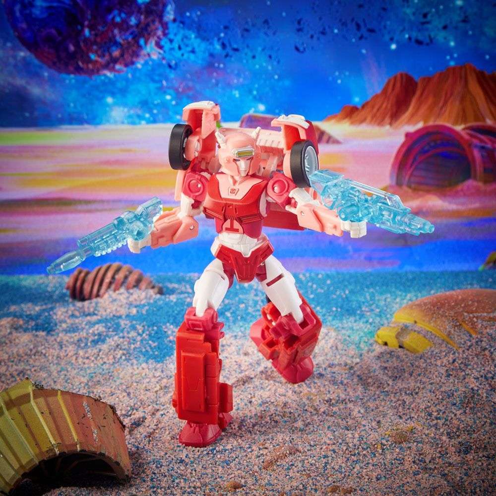 Hasbro Transformers Legacy Elita-1 action figure in pink and white, holding two translucent blue blasters on a planet.
