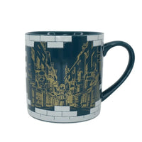 HMB Harry Potter Diagon Alley ceramic mug in dark blue with a gold street illustration and white brick border detail.