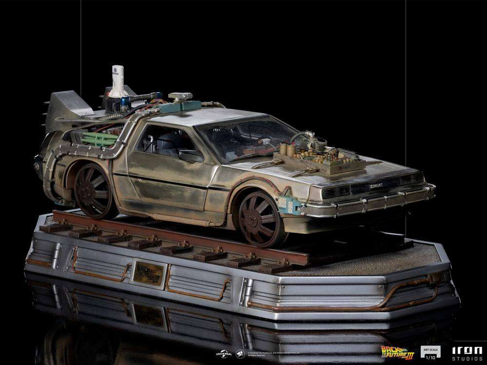 Side view of the Iron Studios Back to the Future III 1/10 scale DeLorean statue on a weathered train track display base.
