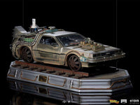 Side view of the Iron Studios Back to the Future III 1/10 scale DeLorean statue on a weathered train track display base.