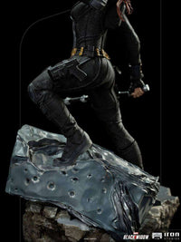Side view of Iron Studios Black Widow 1/10 scale statue in a black tactical suit standing on a rocky, cratered base.
