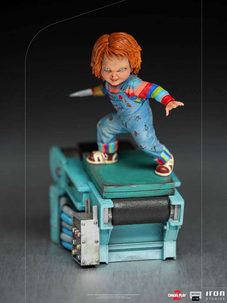 Iron Studios 1/10 scale Chucky statue from Child's Play 2, featuring the doll with a blade hand on a factory base.