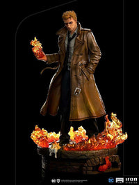 Iron Studios 1/10 Constantine statue in a brown trench coat, holding magical fire over a burning brick base.