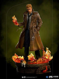 Iron Studios 1/10 Constantine statue wearing a brown trench coat, holding magical fire over a flaming stone base.