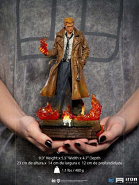 Iron Studios 1/10 Constantine statue in a brown trench coat, holding magical fire over a brick base with flames.