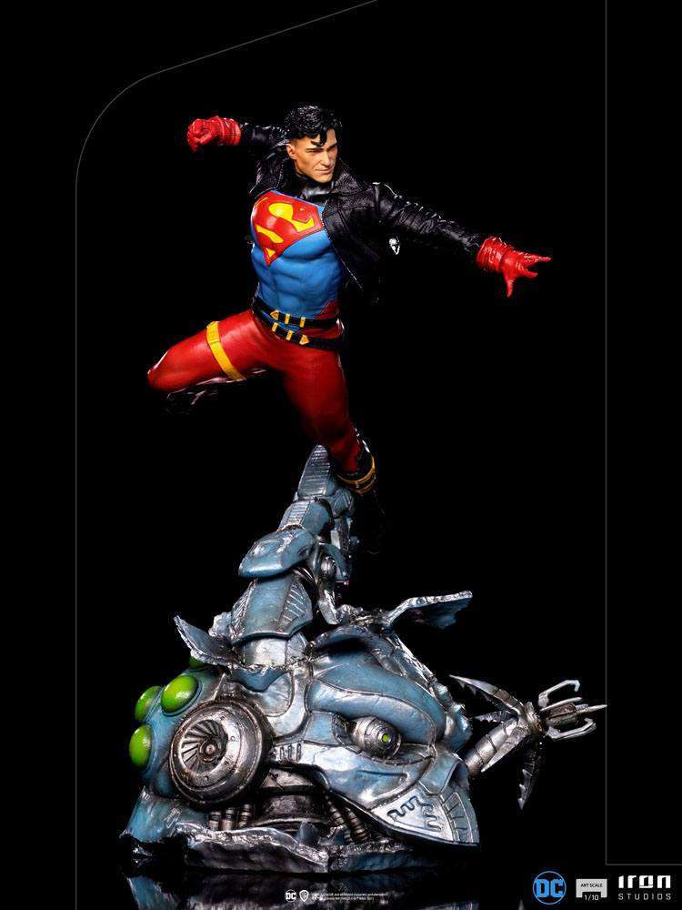 Iron Studios 1/10 Superboy Deluxe Art Scale statue in a dynamic flying pose atop a metallic, battle-damaged base.