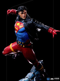 Iron Studios 1/10 Superboy statue in a dynamic flying pose, wearing a blue suit, red pants, and a black leather jacket.