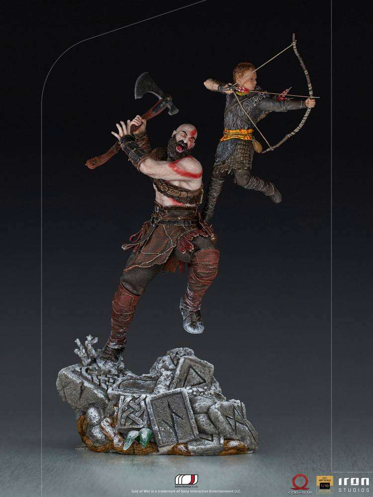 Iron Studios 1/10 Kratos and Atreus statue showing Kratos swinging his axe while Atreus aims his bow on a rocky base.
