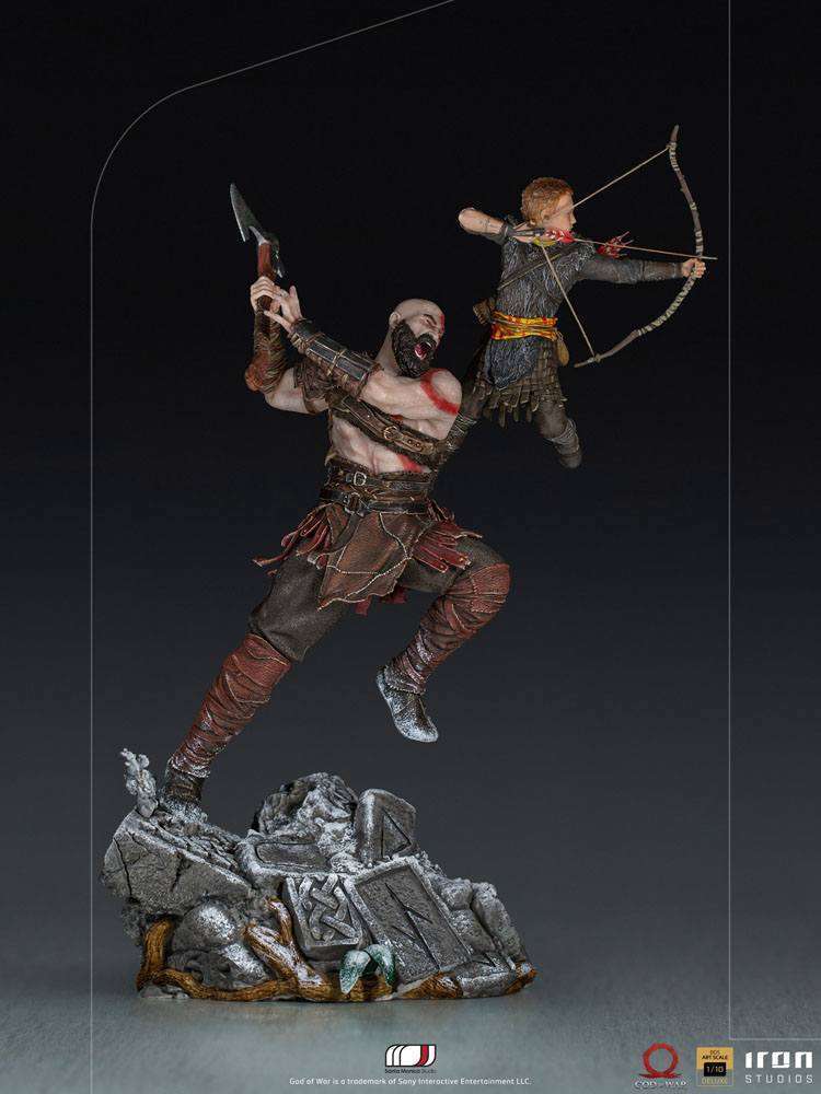 Iron Studios 1/10 Kratos and Atreus statue showing Kratos swinging an axe while Atreus aims a bow on a rocky base.
