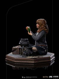 Side view of Iron Studios Hermione Granger Polyjuice 1/10 scale statue holding a green potion vial by a cauldron.