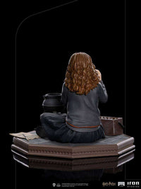 Back view of Iron Studios 1/10 Hermione Granger Polyjuice statue showing her brown hair, grey sweater, and black skirt.