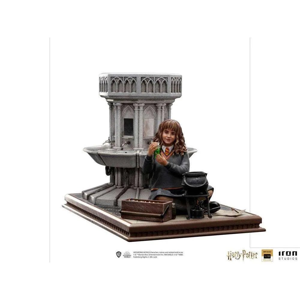 Iron Studios 1/10 Hermione Granger Polyjuice statue sitting by a stone fountain with a potion vial and cauldron.