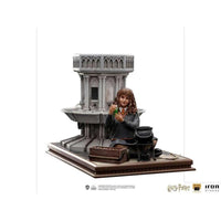 Iron Studios 1/10 Hermione Granger Polyjuice statue sitting by a stone fountain with a potion vial and cauldron.