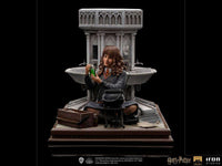 Iron Studios 1/10 Hermione Granger Polyjuice statue sits before a stone fountain with a cauldron and potion vial.