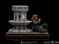 Iron Studios Hermione Granger Polyjuice 1/10 scale statue sitting beside a stone fountain in a side-view display.