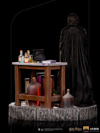 Back view of Iron Studios Severus Snape 1/10 scale statue with a wooden potion table and glass bottles on stone base.