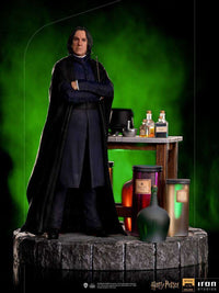 Iron Studios 1/10 Severus Snape statue standing with arms crossed, featuring a potion desk and green background.