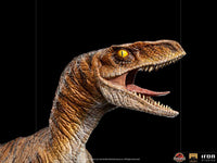 Close-up of the Iron Studios Jurassic World The Lost World 1/10 Velociraptor statue with detailed brown skin and yellow eyes.