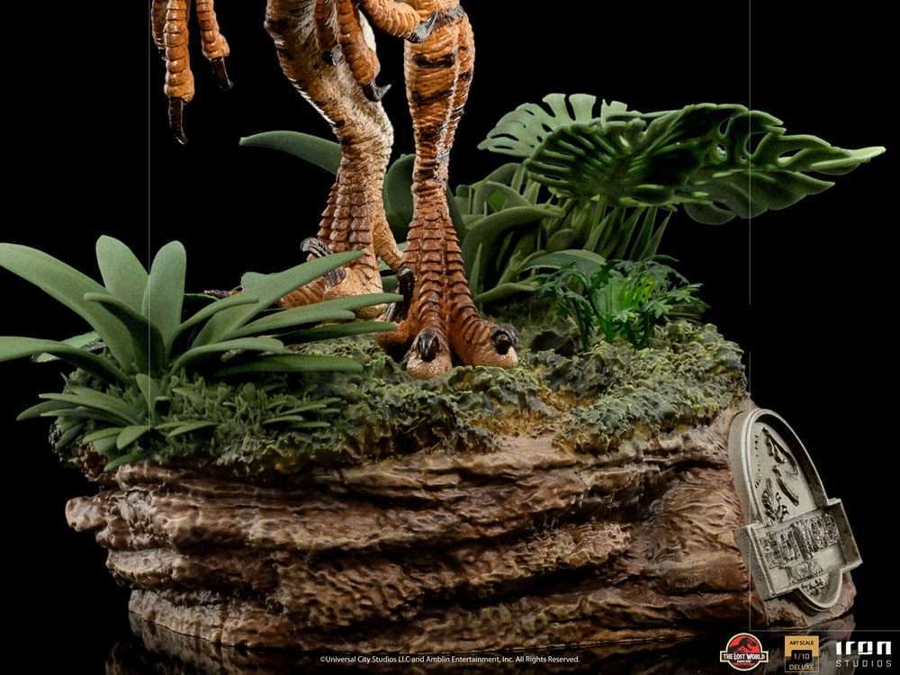 Close-up of the Iron Studios Jurassic World Velociraptor 1/10 scale statue base with jungle foliage and rocky terrain.