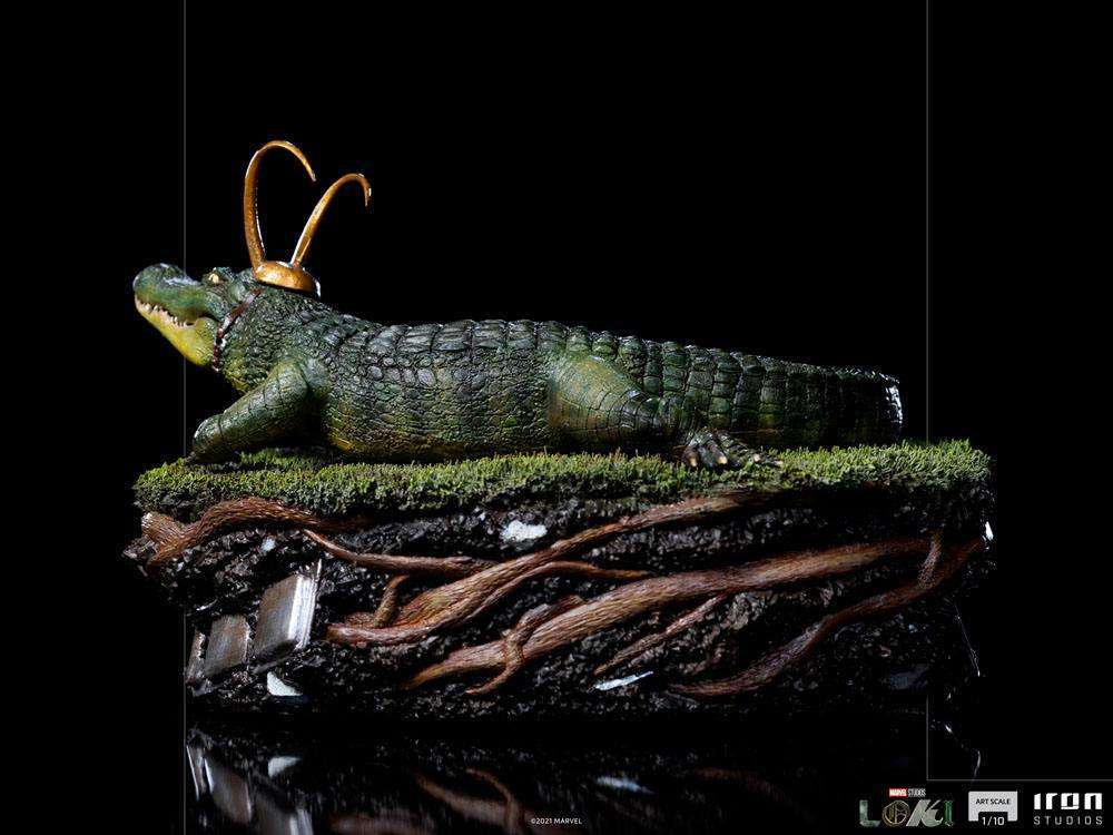Side view of Iron Studios 1/10 scale Alligator Loki statue featuring a green textured reptile on a grassy base.