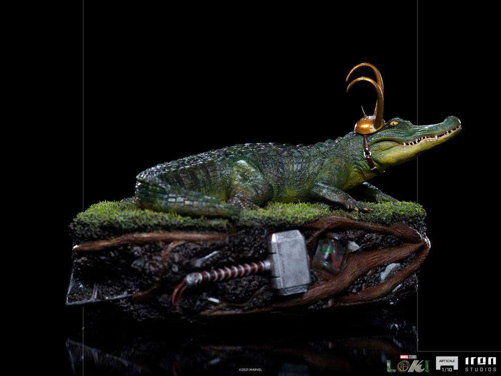 Side view of the 15cm Iron Studios Alligator Loki 1/10 scale statue wearing a golden horned helmet on a mossy base.