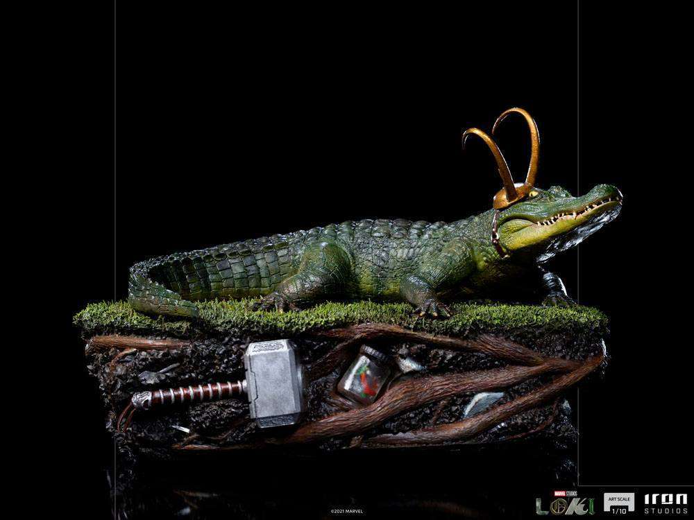 Side view of Iron Studios 1/10 Alligator Loki statue featuring a detailed green reptile with gold horns on a base.