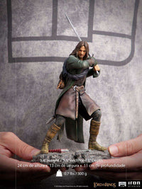 Iron Studios 1/10 scale Aragorn statue in a dynamic combat pose with sword, wearing a green cloak and leather gear.