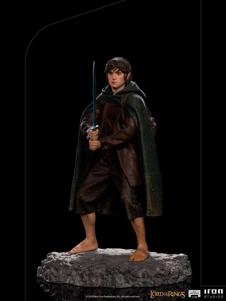 Iron Studios 1/10 scale Frodo statue standing on a rocky base, holding Sting in a front view against a black background.