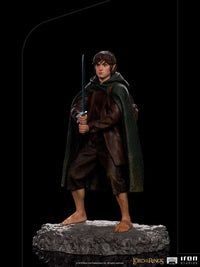 Iron Studios 1/10 scale Frodo statue standing on a rocky base, holding Sting in a front view against a black background.