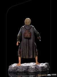 Back view of Iron Studios 1/10 Merry statue, showing detailed brown cloak, backpack, and rocky base on black background.