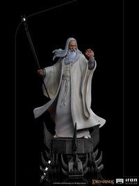 Iron Studios Saruman 1/10 scale statue in white robes, holding a staff and Palantir on a dark, spiked base.