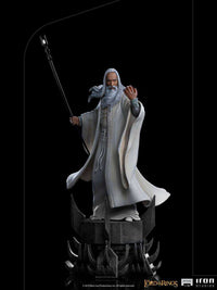 Iron Studios 1/10 Saruman statue from Lord of the Rings, featuring the wizard in white robes holding a staff on a base.