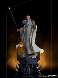 Iron Studios Saruman 1/10 scale statue featuring the wizard in white robes holding a staff on a dark, spiked base.