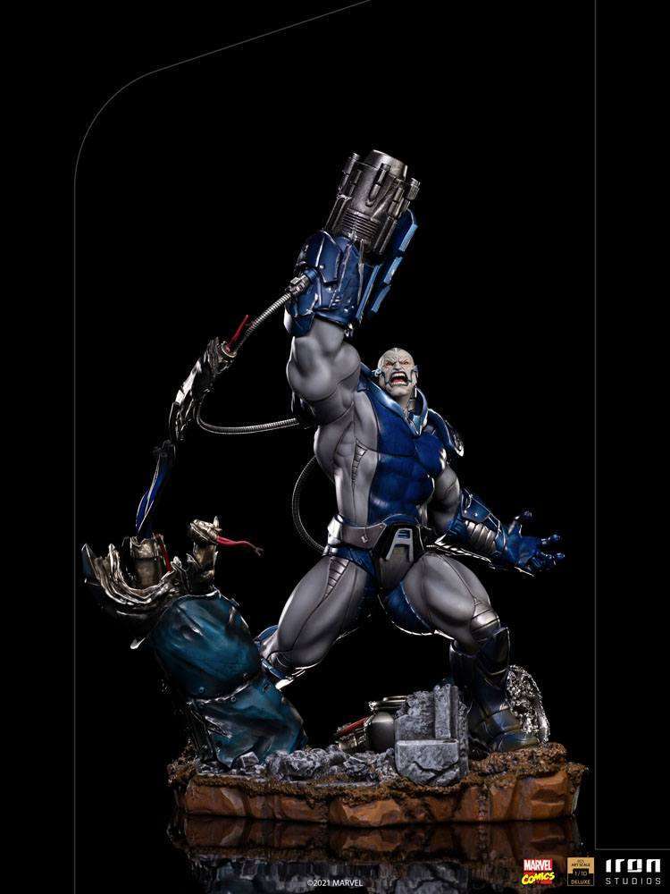 Iron Studios 1/10 scale Apocalypse Deluxe statue in blue and grey armor, featuring a raised cannon arm on a rubble base.