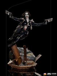 Iron Studios 1/10 Domino statue in a dynamic leaping pose, wearing a black tactical suit and dual-wielding pistols.