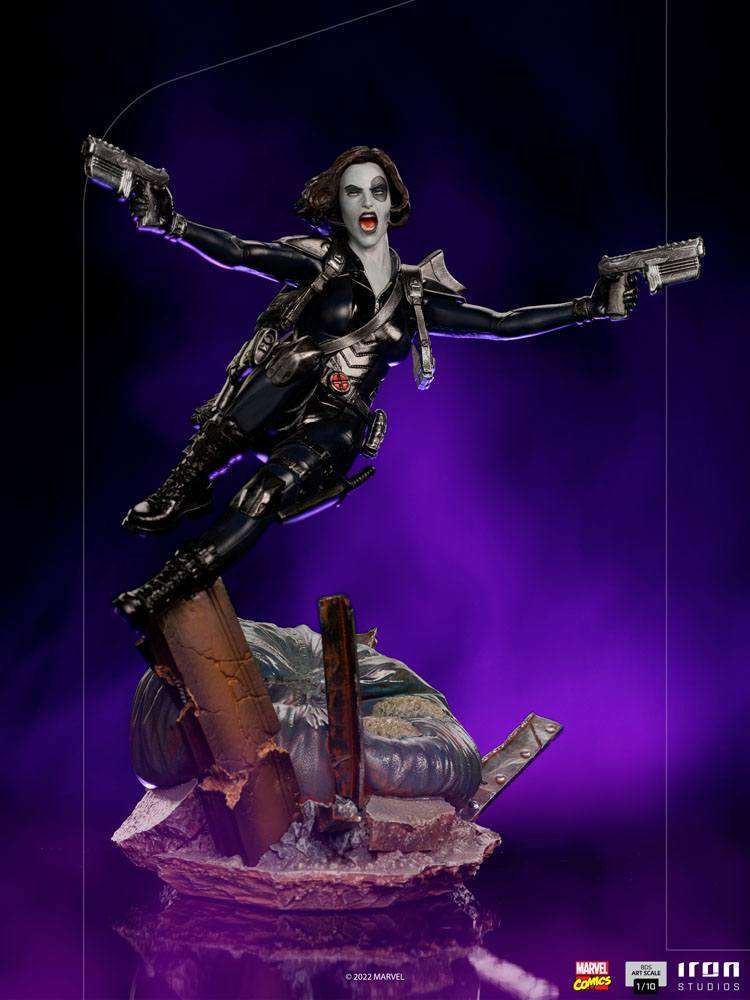 Iron Studios 1/10 scale Domino statue in a dynamic leaping pose with dual pistols against a purple background.