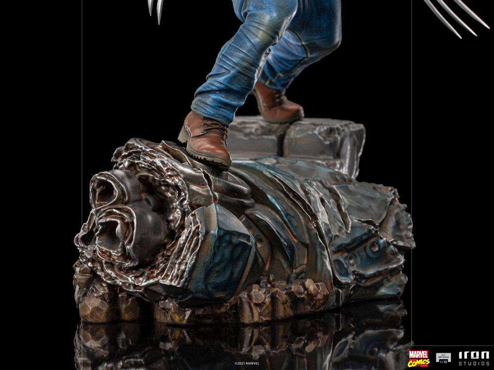 Iron Studios 1/10 Logan statue showing blue jeans and brown boots standing on a detailed, weathered metallic base.