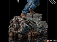 Iron Studios 1/10 Logan statue showing blue jeans and brown boots standing on a detailed, weathered metallic base.