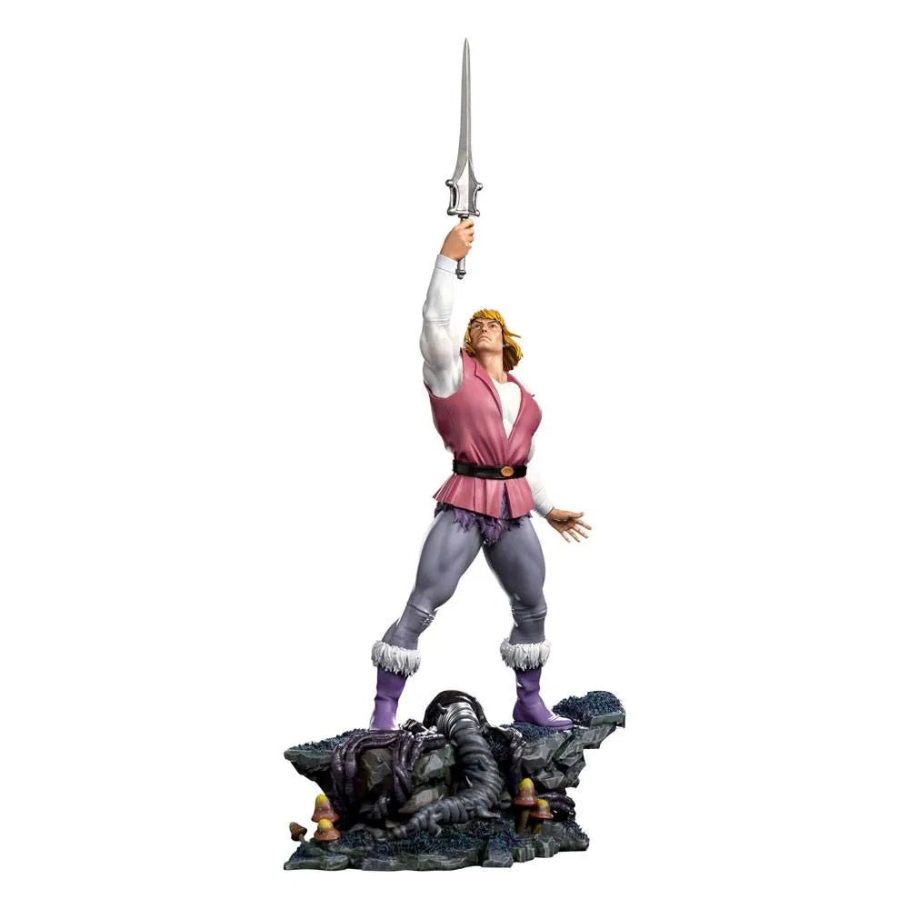 Iron Studios Prince Adam 1/10 scale statue holding a sword aloft on a detailed rocky base with mushrooms.