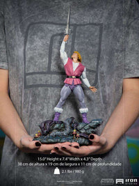 Iron Studios 1/10 Prince Adam statue holding the Power Sword aloft on a detailed rocky base, held in hands.