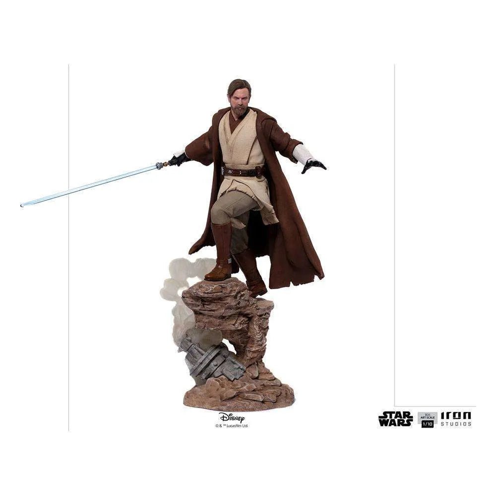 Iron Studios 1/10 Obi-Wan Kenobi statue in brown robes holding a blue lightsaber on a rocky base, full-body front view.