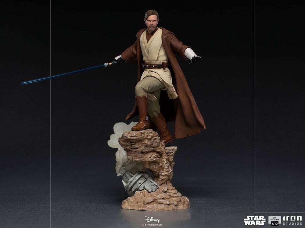 Iron Studios 1/10 Obi-Wan Kenobi statue in brown Jedi robes holding a blue lightsaber on a rocky desert base.