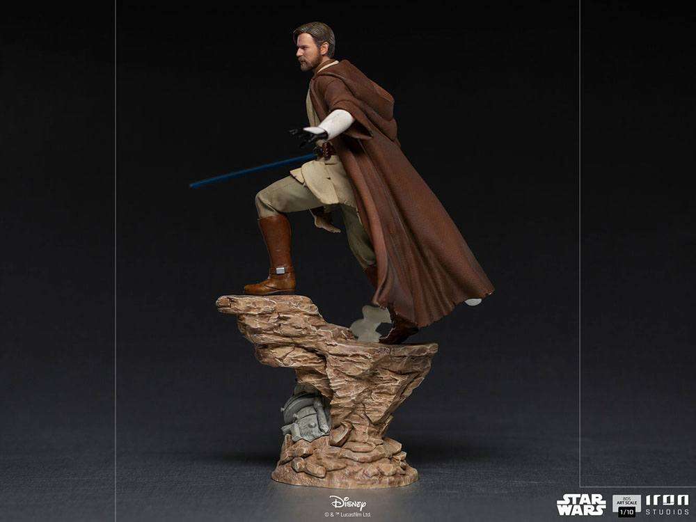 Side view of Iron Studios 1/10 Obi-Wan Kenobi statue in brown robes with a blue lightsaber on a rocky base.