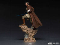 Side view of Iron Studios 1/10 Obi-Wan Kenobi statue in brown robes with a blue lightsaber on a rocky base.