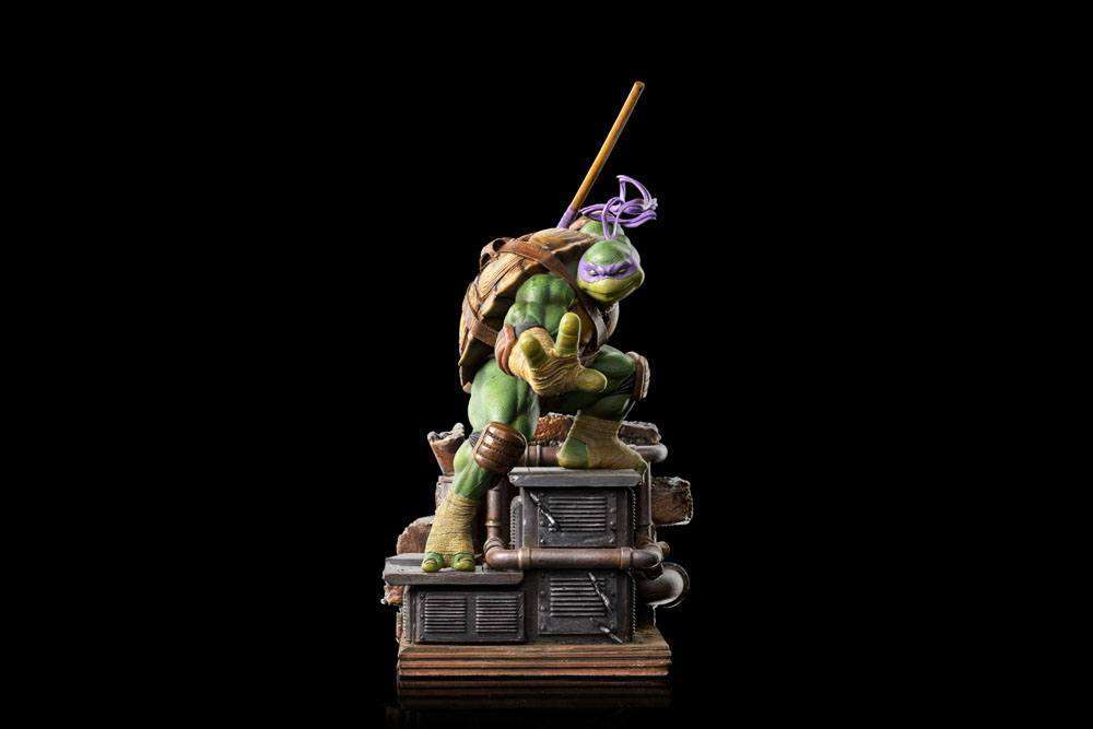 Iron Studios 1/10 scale Donatello statue in a dynamic pose, standing on a detailed industrial rooftop base.