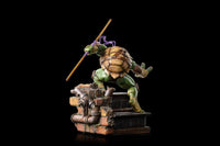 Rear view of Iron Studios Donatello 1/10 scale statue holding a bo staff on a detailed brick and pipe base.