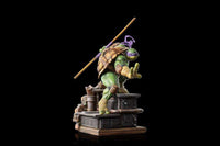 Side view of Iron Studios Donatello 1/10 scale statue with bo staff, wearing a purple mask on a sewer base.